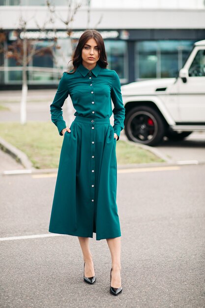 Full length photo of gorgeous lady in green dress standing outdoors while posing at camera. Style and fashion concept