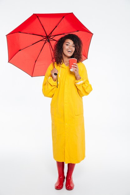 Full length picture of smiling african woman in raincoat