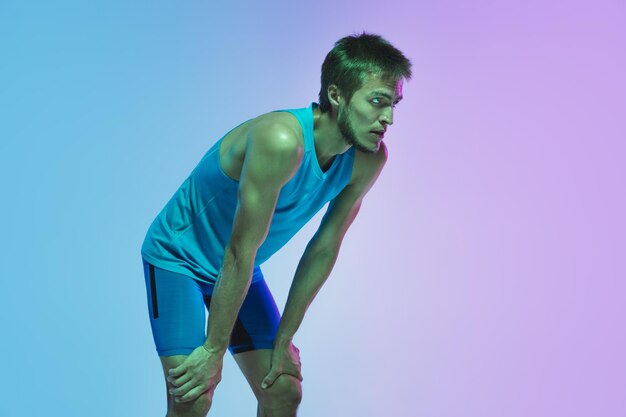 Full length portrait of active young caucasian running, jogging man on in neon
