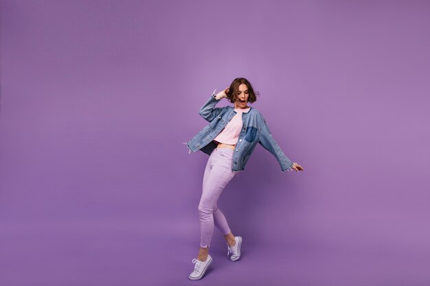 Full-length portrait of attractive slim girl wears white sport shoes. Indoor photo of enchanting caucasian woman dancing.