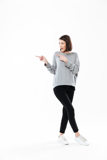 Full length portrait of a casual woman pointing two fingers