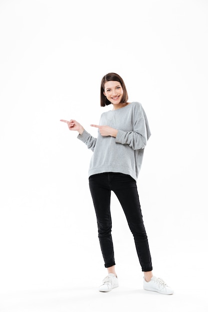 Full length portrait of a casual woman pointing two fingers