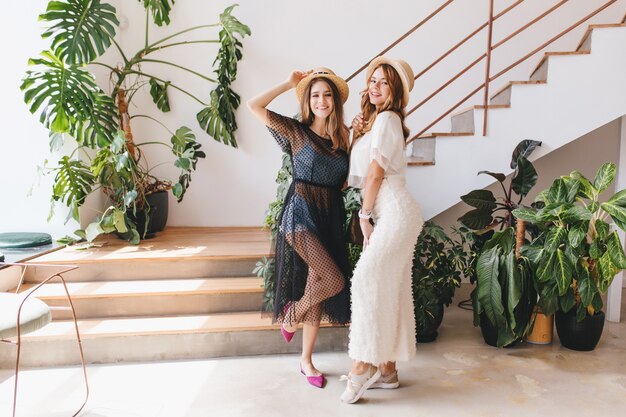 Full-length portrait of cheerful girls dancing together on stairs and laughing