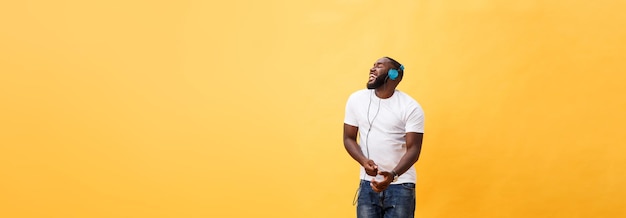 Free photo full length portrait of a cherry young african american man listening to music with headphones and d