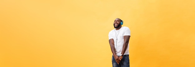 Full length portrait of a cherry young african american man listening to music with headphones and d