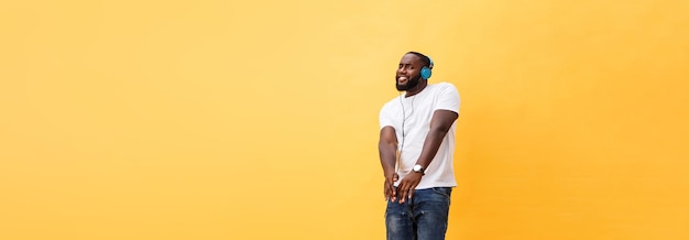 Free photo full length portrait of a cherry young african american man listening to music with headphones and d