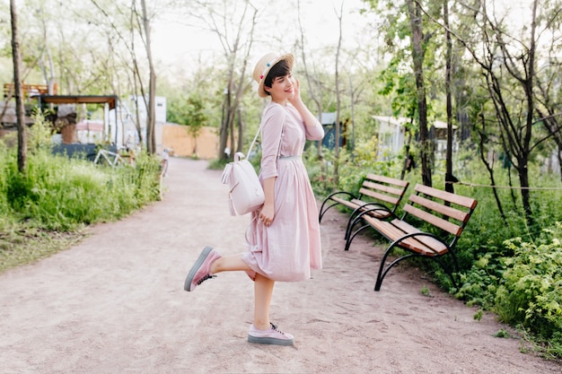 朝の公園の路地の真ん中でポーズをとって、かわいい黒髪の女性の全身像