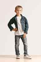 Free photo full length portrait of cute little kid boy in stylish jeans clothes and smiling, standing on white. kids fashion concept