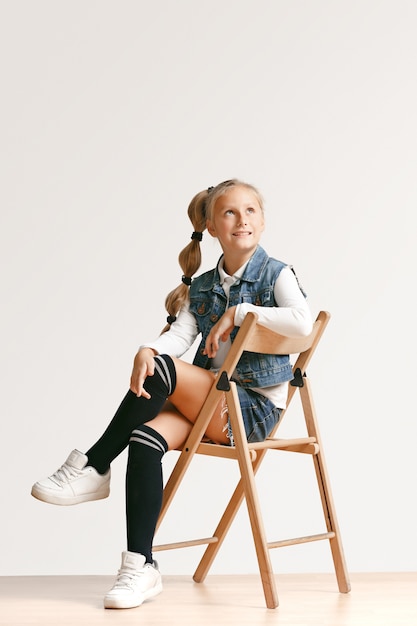 Full length portrait of cute little kid girl in stylish jeans clothes and smiling, standing on white. Kids fashion concept