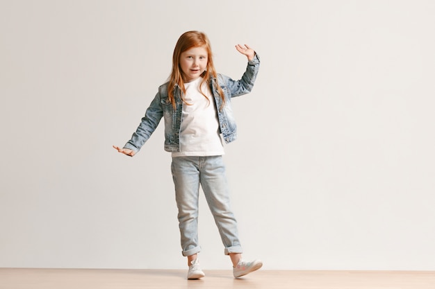 Il ritratto integrale del bambino sveglio nel jeans alla moda copre sorridere