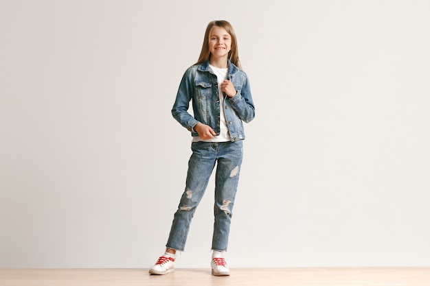 Full length portrait of cute little teen in stylish jeans clothes smiling