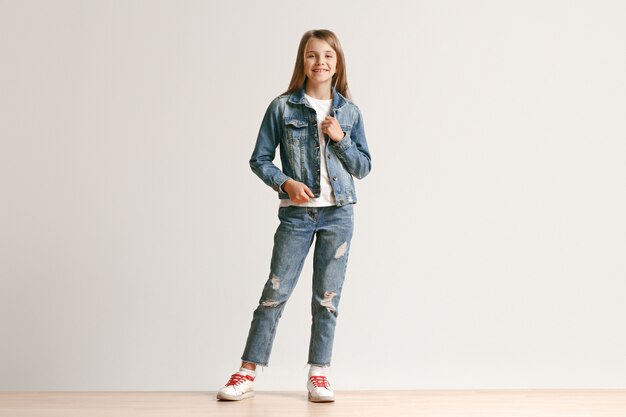 Полная длина портрет милой маленькой девочки в стильной джинсовой одежде улыбается