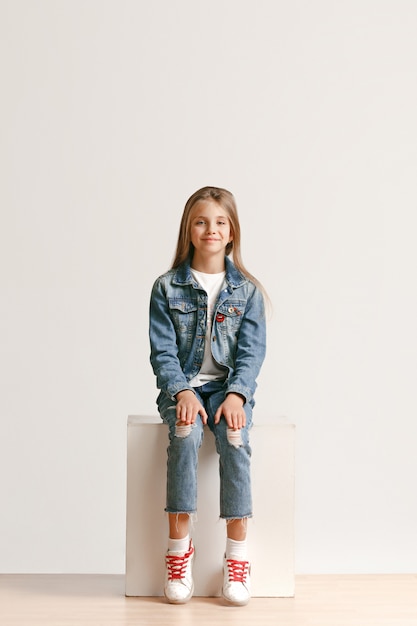 笑顔のスタイリッシュなジーンズ服でかわいい小さな10代の完全な長さの肖像画