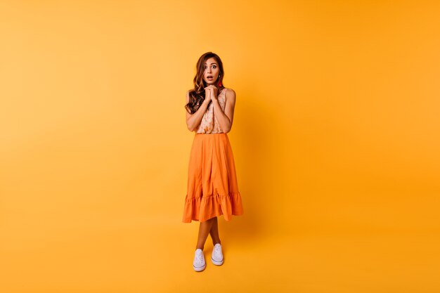 Full-length portrait of debonair ginger woman in long skirt. Gorgeous lady wears orange clothes posing in studio.