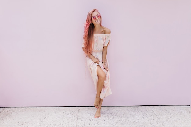 Full-length portrait of dreamy tanned woman wears sunglasses and long summer dress.