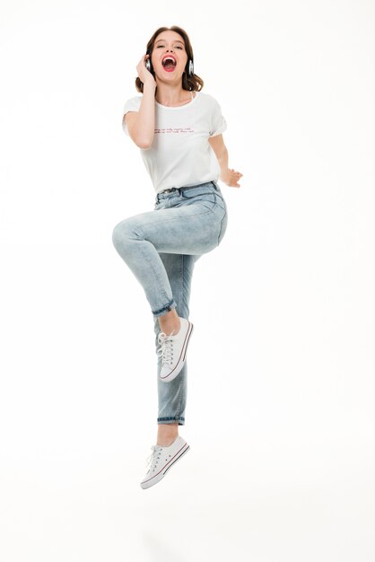 full length portrait of a excited girl listening to music