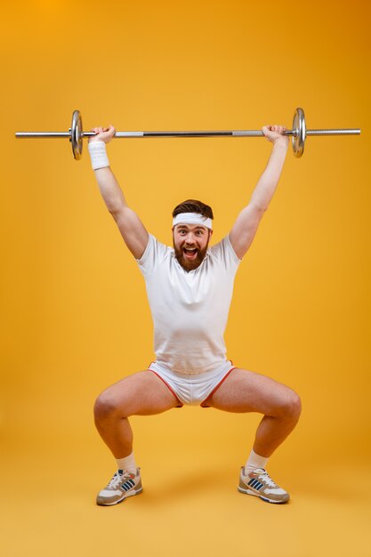 Full length portrait of a fitness man squatting with barbell