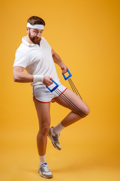 Foto gratuita ritratto integrale di un allenamento dell'uomo di forma fisica con l'espansore