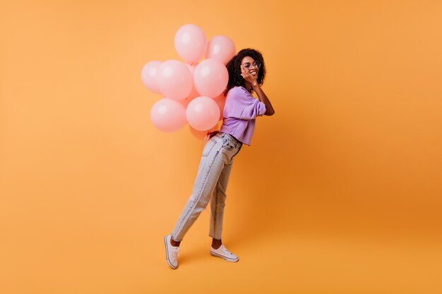 Full-length portrait of glad african woman waiting for party. Spectacular female model with curly hairstyle expressing happiness in her birthday.