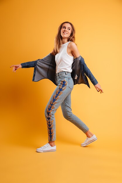 Full length portrait of a happy cheerful girl walking