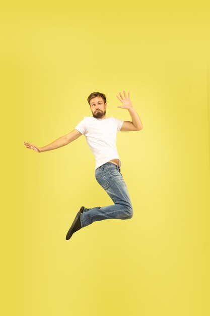 노란색 배경에 고립 행복 점프 남자의 전체 길이 초상화. 캐주얼 옷에 백인 남성 모델입니다. 선택의 자유, 영감, 인간의 감정 개념. 5, 인사, 자신감을줍니다.