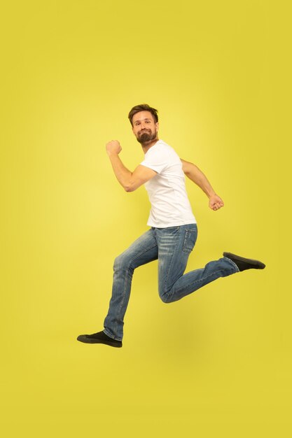 노란색 배경에 고립 행복 점프 남자의 전체 길이 초상화. 캐주얼 옷에 백인 남성 모델입니다. 선택의 자유, 영감, 인간의 감정 개념. 행복하게 달리기.