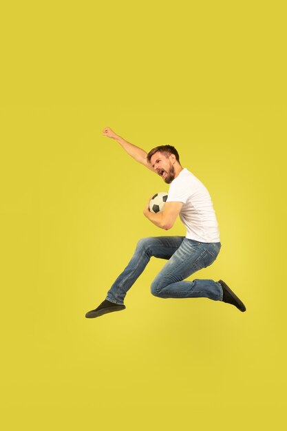 노란색 배경에 고립 행복 점프 남자의 전체 길이 초상화. 캐주얼 옷에 백인 남성 모델