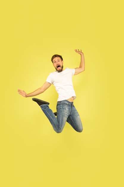 Full length portrait of happy jumping man isolated on yellow