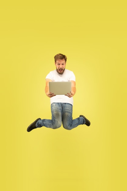 Free photo full length portrait of happy jumping man isolated on yellow