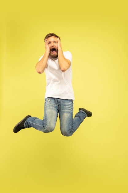 Full length portrait of happy jumping man isolated on yellow