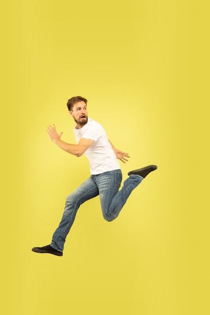 Full length portrait of happy jumping man isolated on yellow