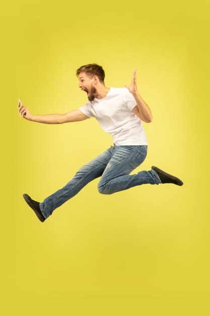 Full length portrait of happy jumping man isolated on yellow