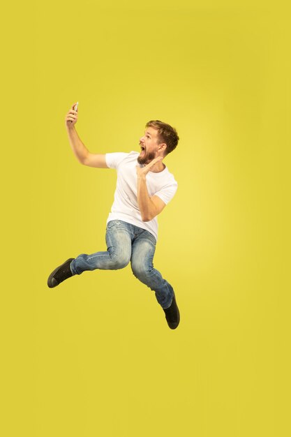 Full length portrait of happy jumping man isolated on yellow