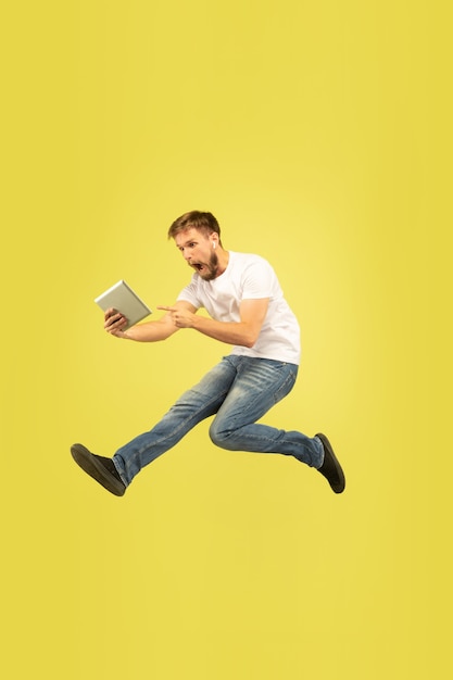 Полный портрет счастливого прыгающего человека на желтом фоне