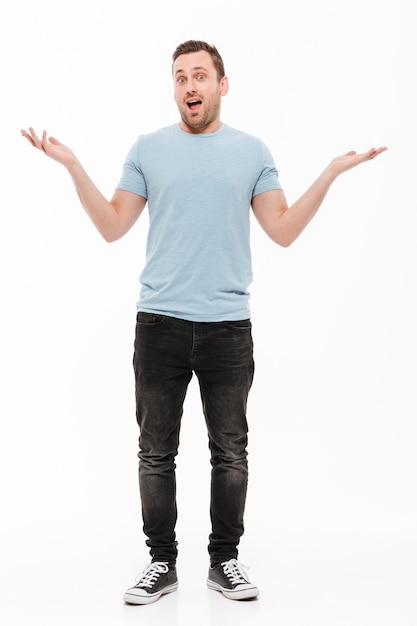 Full-length portrait of happy man with stubble in casual throwing up arms, expressing surprise or excitement