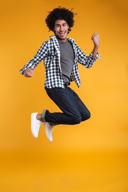 Полнометражный портрет счастливого молодого африканского человека скача