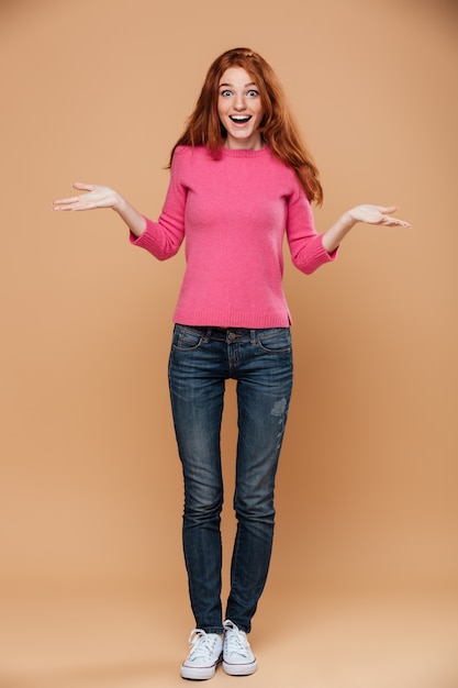 Full length portrait of a happy young redhead girl with open hands