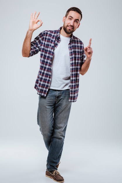 Full length portrait man showing ok sign and pointing up
