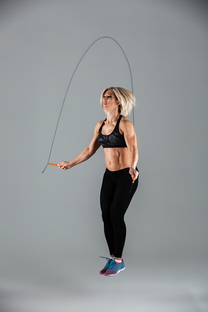 Full length portrait of a muscular adult sportswoman jumping