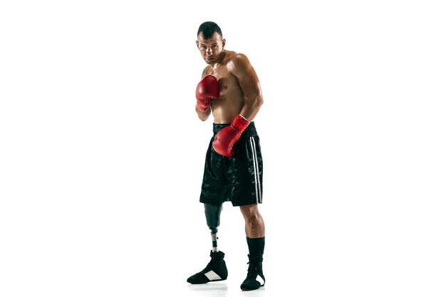 Full length portrait of muscular sportsman with prosthetic leg, copy space. Male boxer in red gloves. Isolated shot on white  wall.