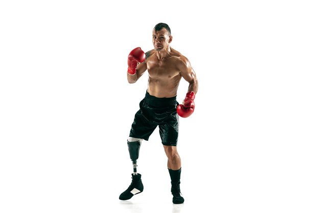 Full length portrait of muscular sportsman with prosthetic leg, copy space. Male boxer in red gloves. Isolated shot on white  wall.