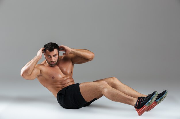 Full length portrait of a muscular strong shirtless male bodybuilder