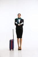 Полнометражный портрет молодой женщины, стюардессы с чемоданом, позирует изолированным на белом фоне