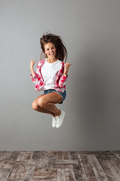 Free photo full-length portrait of pretty jumping woman in casual wear