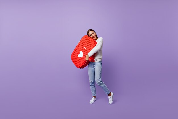 Full-length portrait of refined girl obsessed with social networks. Well-dressed female blogger standing on purple