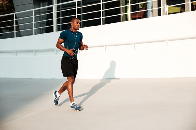 Full length portrait of a serious african sportsman in earphones