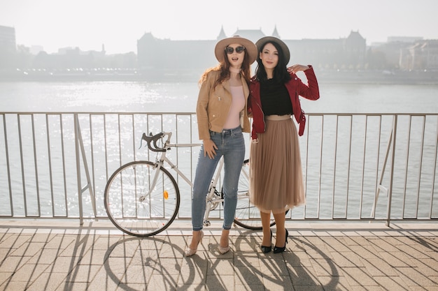 Free photo full-length portrait of shapely white woman in jeans spending time with brunette sister