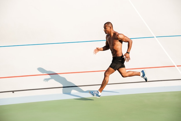 Полнометражный портрет сильного бегущего полуголого спортсмена