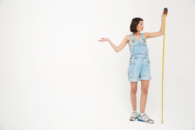 Full length portrait of woman measure herself with tape