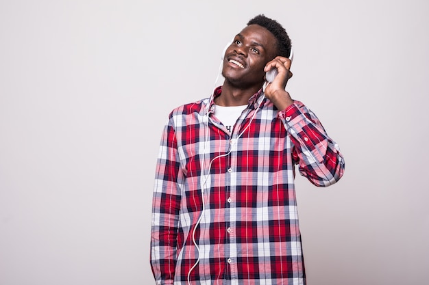 Full length portrait of a young afro american man listening to music with headphones isolated